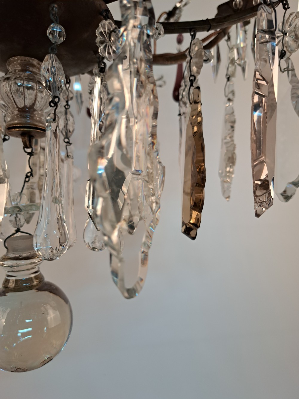 A multi-arm French crystal chandelier with candle-style light sockets, clear faceted glass prisms, and purple teardrop pendants on a dark wrought iron frame. View XXVI