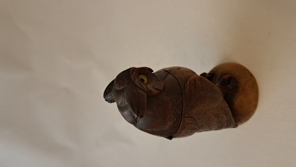 A small carved wooden owl inkwell featuring glass eyes and perched on a circular wooden base against a neutral background. View VII