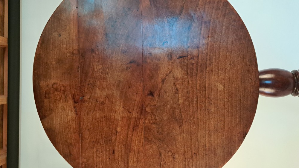 A Georgian mahogany tilt-top table with a circular timber top tilted vertically above a vase-turned pedestal stem and three cabriole legs. View II