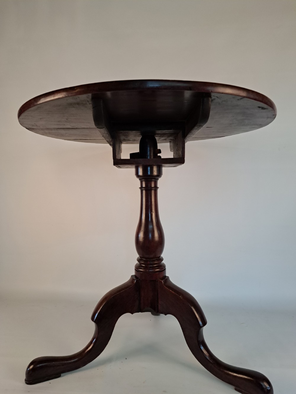 A Georgian mahogany tilt-top table with a circular timber top tilted vertically above a vase-turned pedestal stem and three cabriole legs. View V