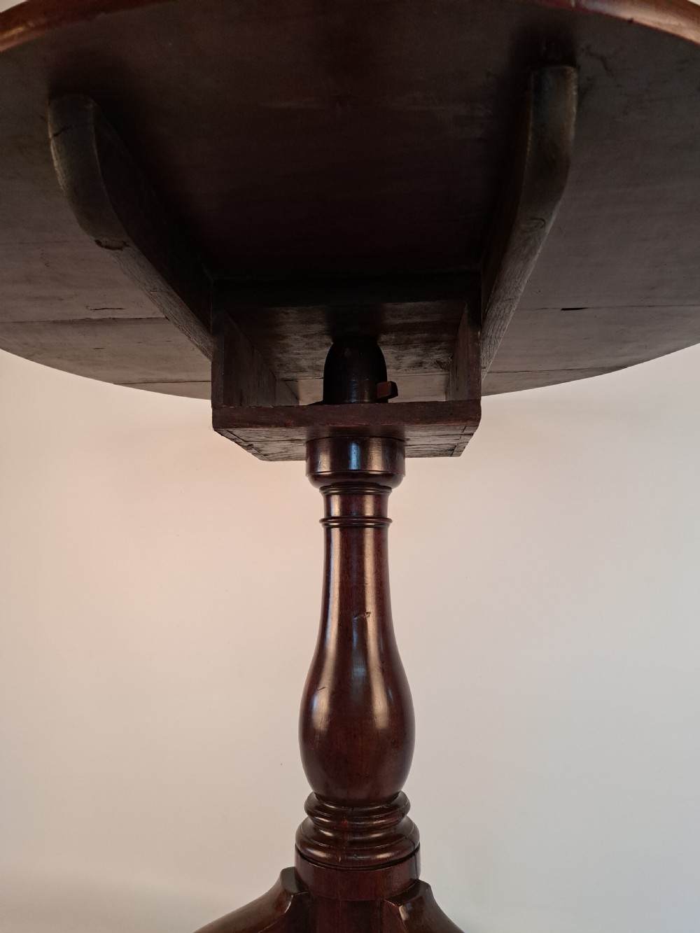 A Georgian mahogany tilt-top table with a circular timber top tilted vertically above a vase-turned pedestal stem and three cabriole legs. View VIII