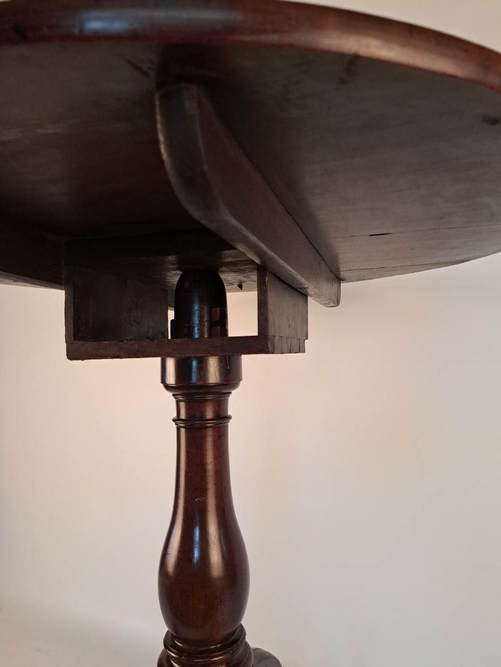 A Georgian mahogany tilt-top table with a circular timber top tilted vertically above a vase-turned pedestal stem and three cabriole legs. View IX
