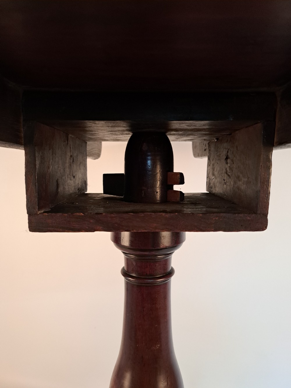 A Georgian mahogany tilt-top table with a circular timber top tilted vertically above a vase-turned pedestal stem and three cabriole legs. View XI