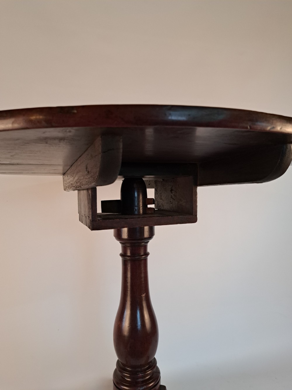 A Georgian mahogany tilt-top table with a circular timber top tilted vertically above a vase-turned pedestal stem and three cabriole legs. View XII