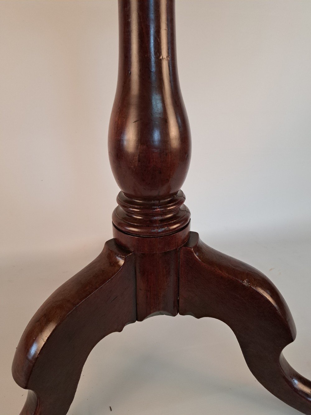A Georgian mahogany tilt-top table with a circular timber top tilted vertically above a vase-turned pedestal stem and three cabriole legs. View XIII