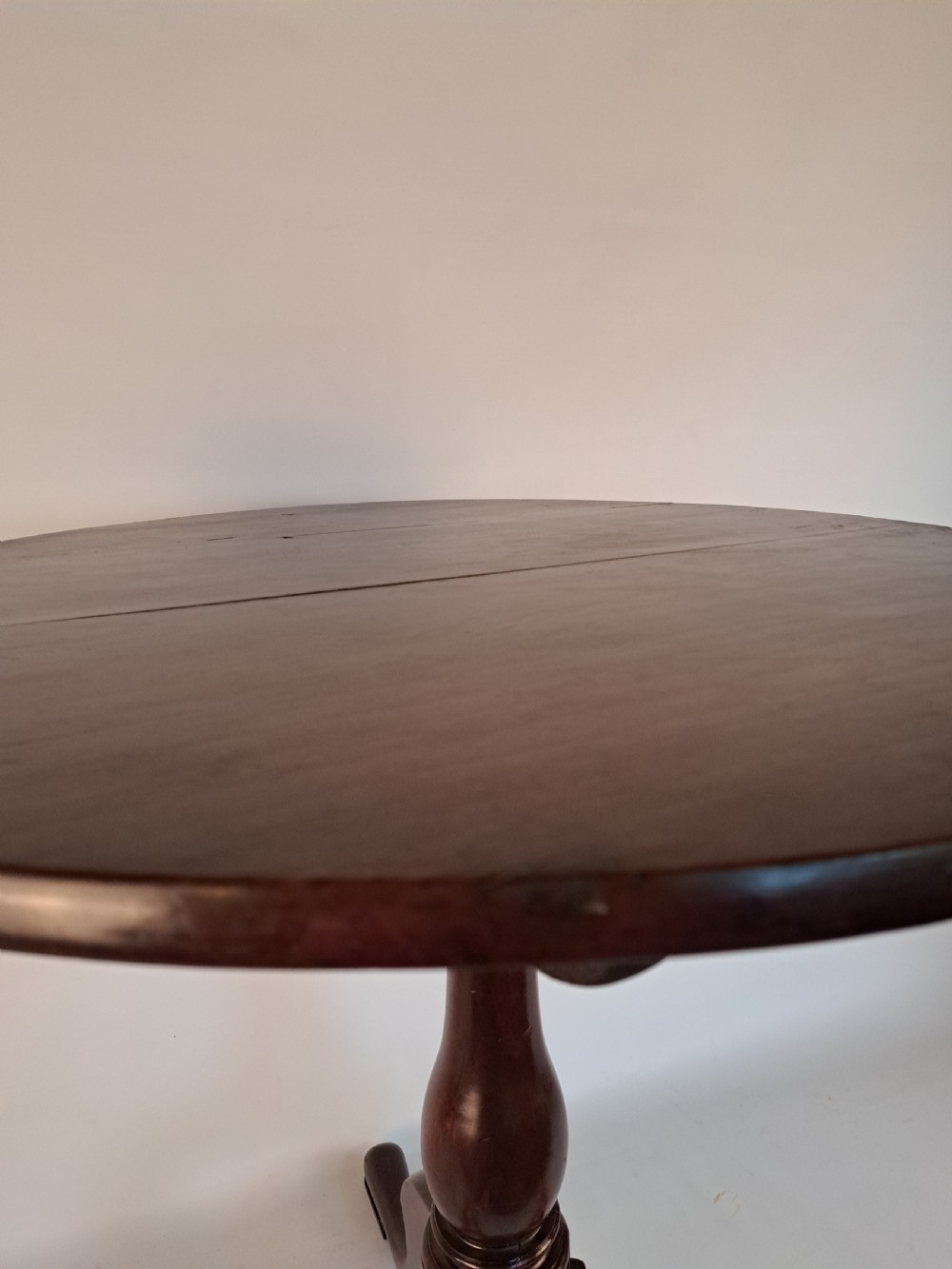 A Georgian mahogany tilt-top table with a circular timber top tilted vertically above a vase-turned pedestal stem and three cabriole legs. View XVI