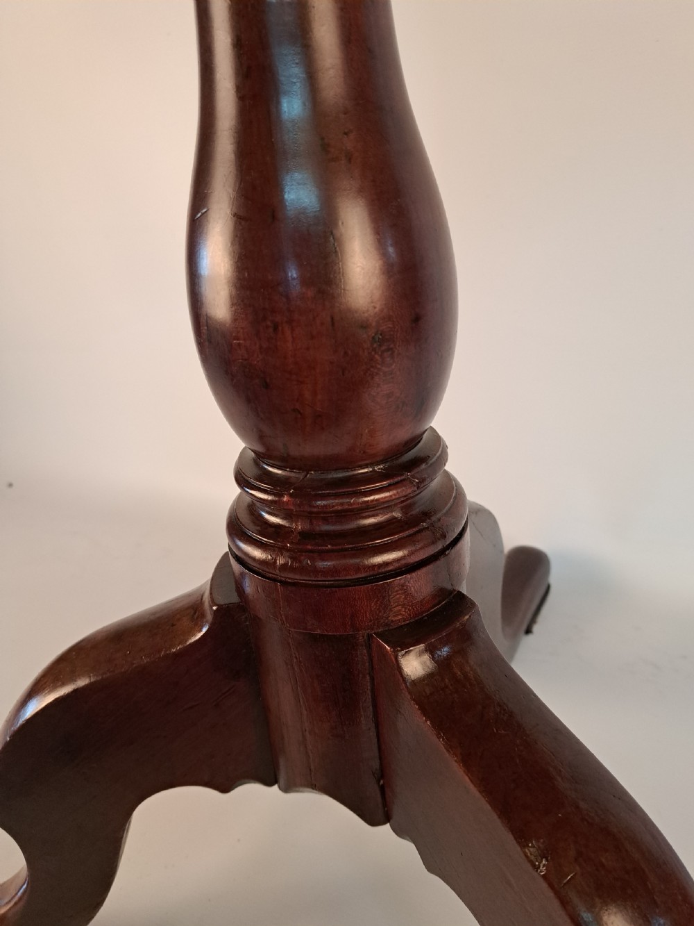 A Georgian mahogany tilt-top table with a circular timber top tilted vertically above a vase-turned pedestal stem and three cabriole legs. View XVII