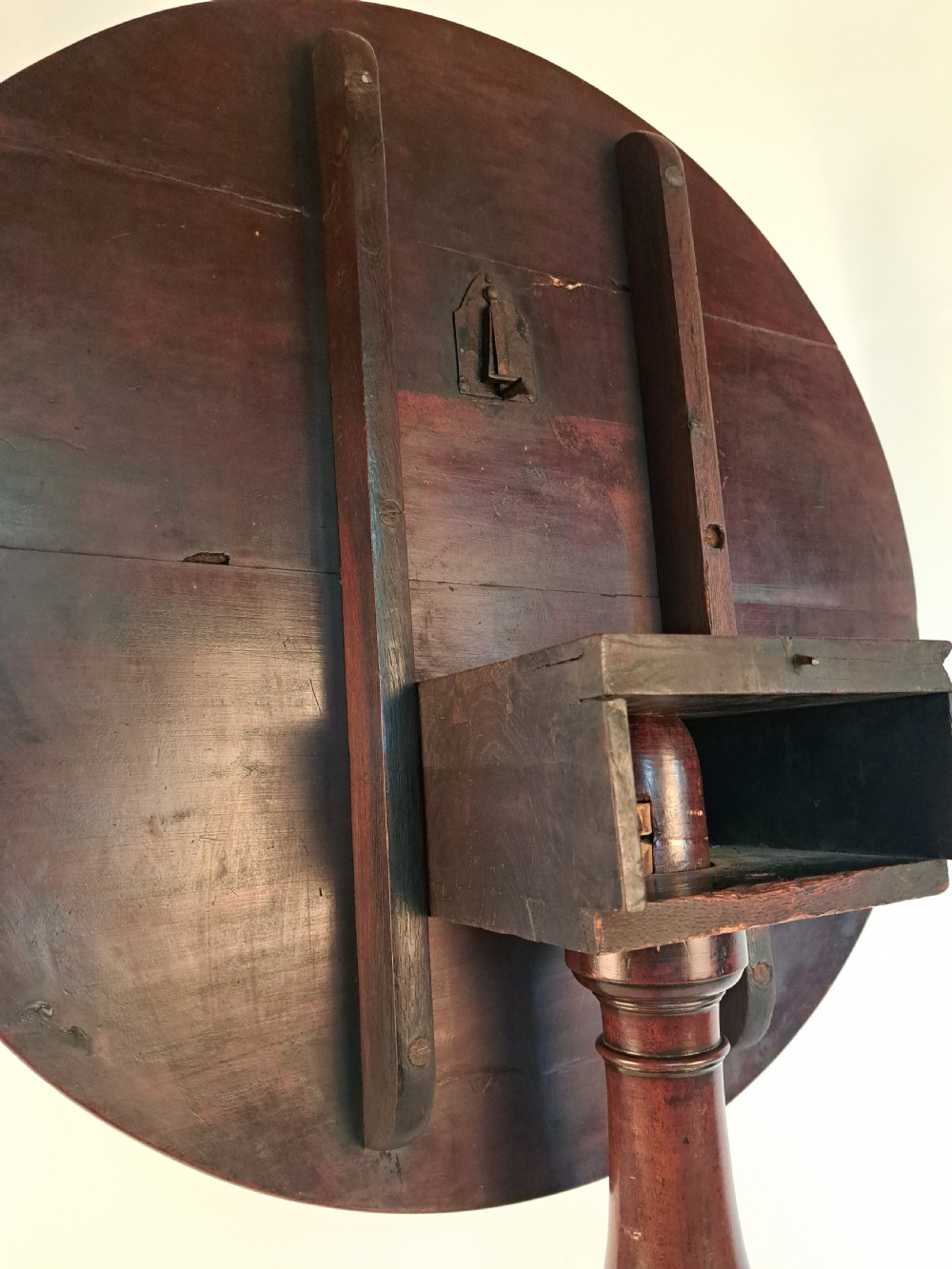 A Georgian mahogany tilt-top table with a circular timber top tilted vertically above a vase-turned pedestal stem and three cabriole legs. View XXII