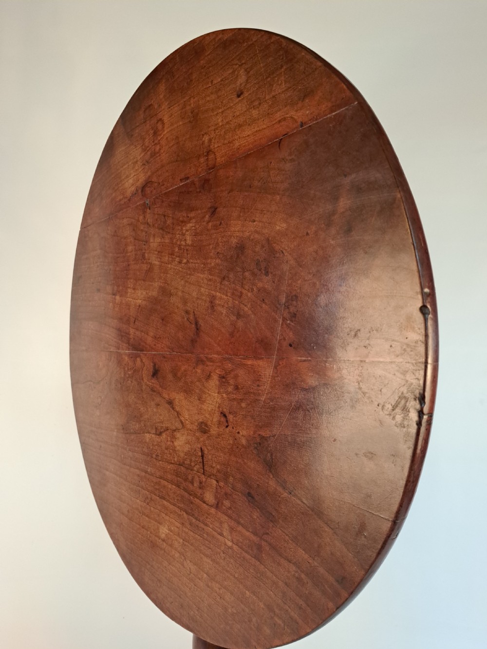 A Georgian mahogany tilt-top table with a circular timber top tilted vertically above a vase-turned pedestal stem and three cabriole legs. View XXIII