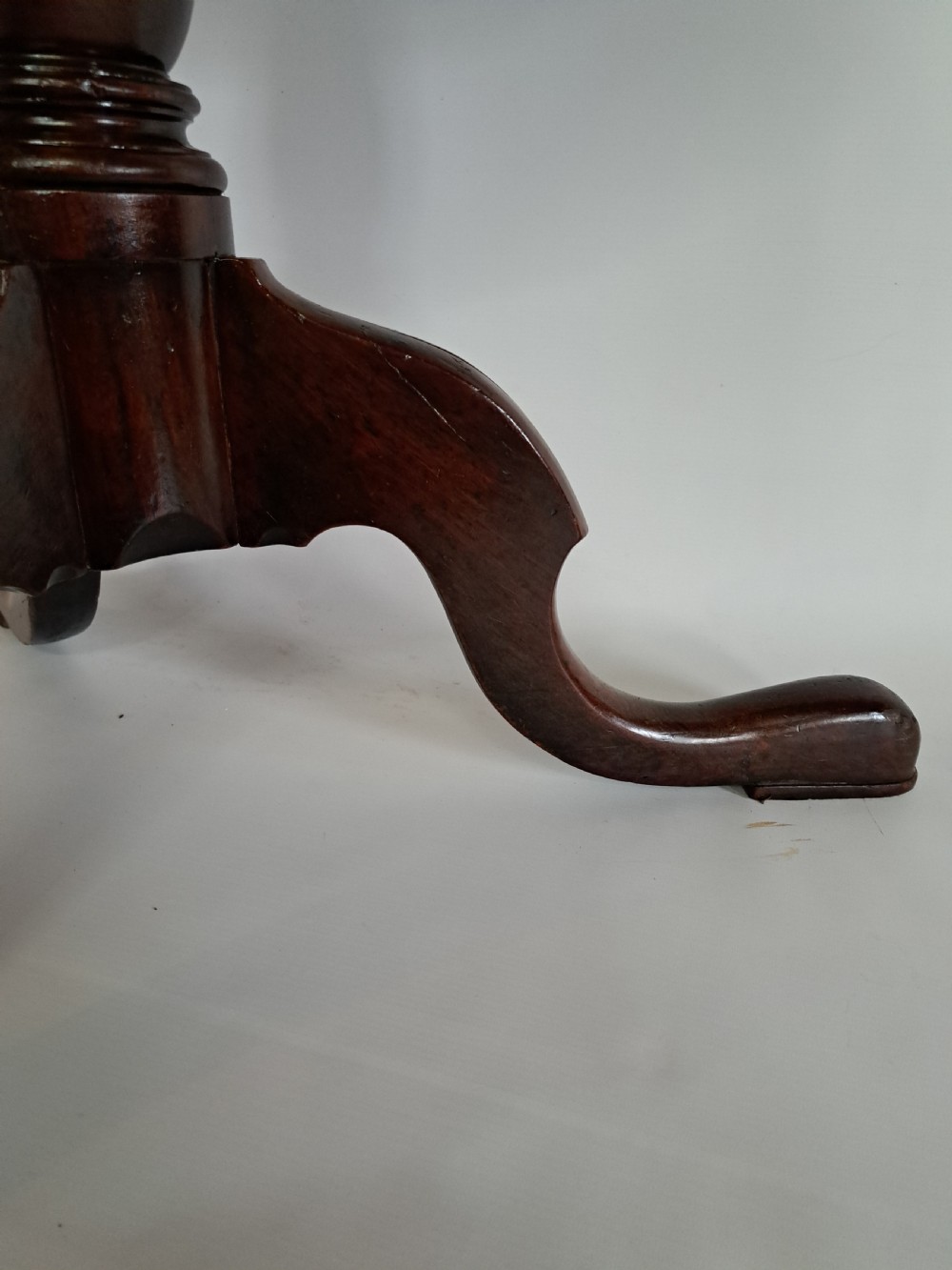 A Georgian mahogany tilt-top table with a circular timber top tilted vertically above a vase-turned pedestal stem and three cabriole legs. View XXIV