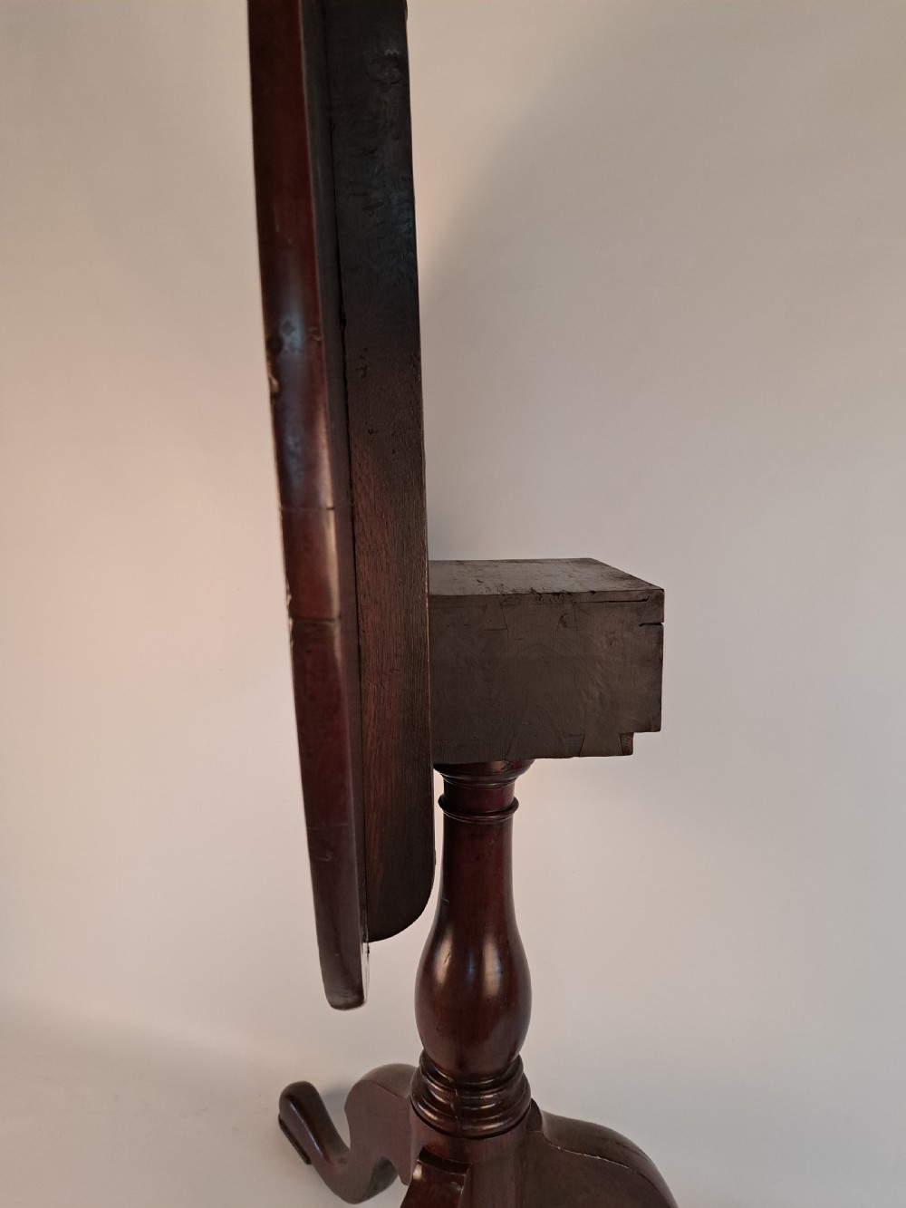 A Georgian mahogany tilt-top table with a circular timber top tilted vertically above a vase-turned pedestal stem and three cabriole legs. View XXIX