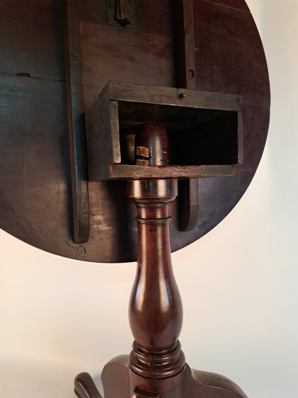 A Georgian mahogany tilt-top table with a circular timber top tilted vertically above a vase-turned pedestal stem and three cabriole legs. View XXX