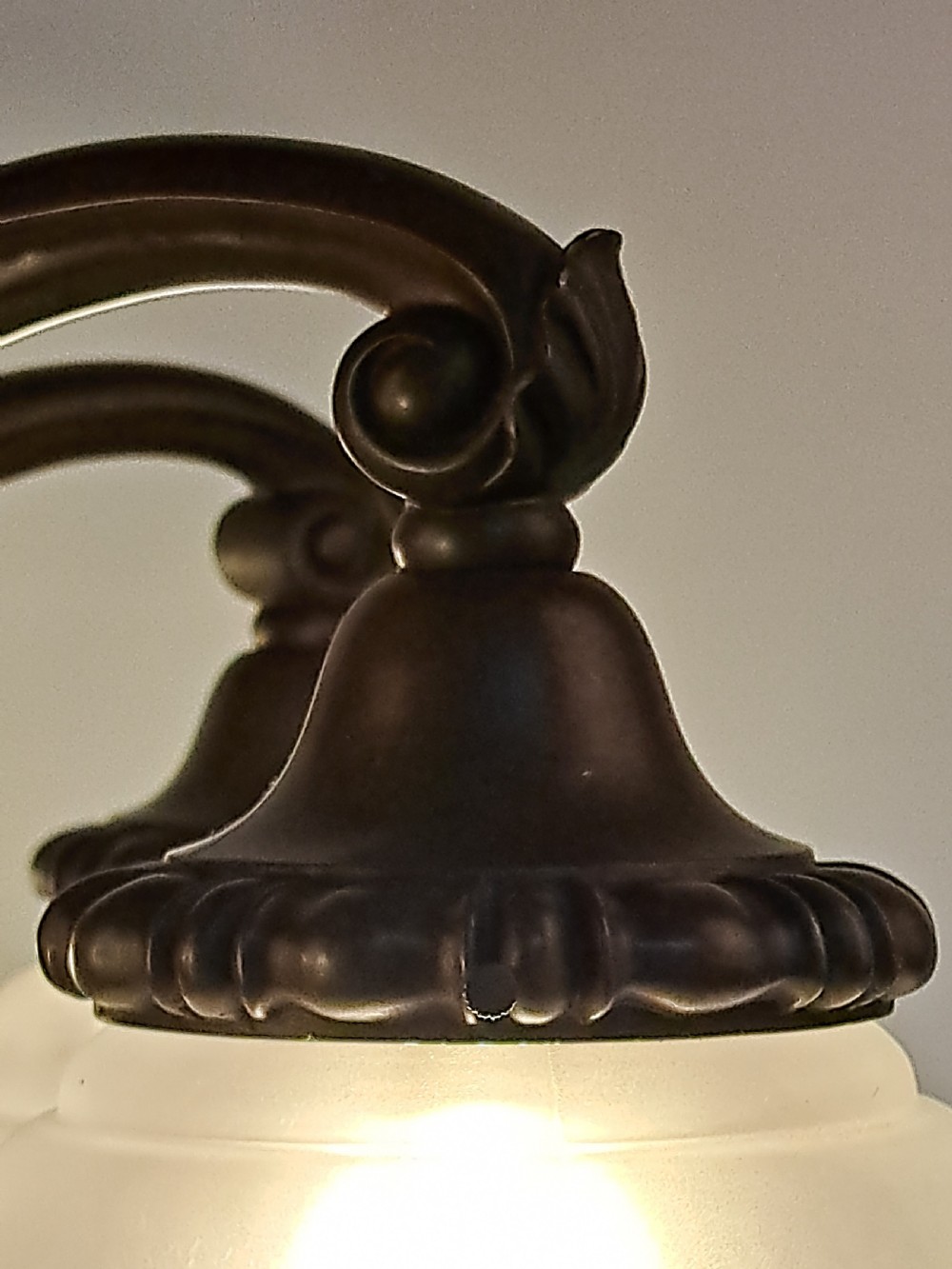 A five-arm dark bronze chandelier featuring a central turned stem, curved scroll arms, and downward-facing frosted glass shades. View X