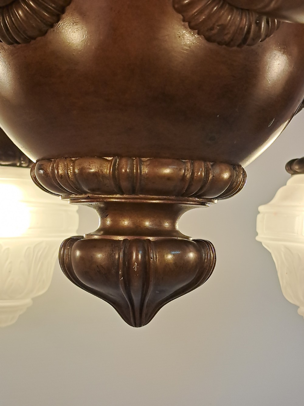 A five-arm dark bronze chandelier featuring a central turned stem, curved scroll arms, and downward-facing frosted glass shades. View XV
