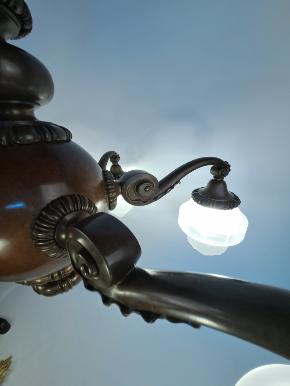 A five-arm dark bronze chandelier featuring a central turned stem, curved scroll arms, and downward-facing frosted glass shades. View XVIII