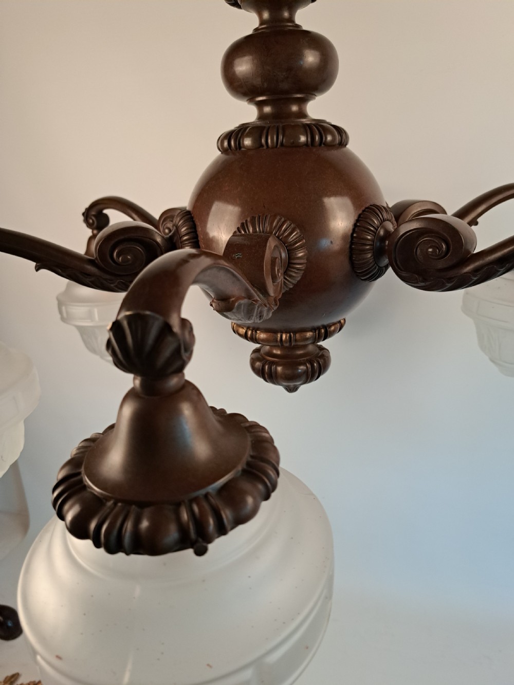 A five-arm dark bronze chandelier featuring a central turned stem, curved scroll arms, and downward-facing frosted glass shades. View XX