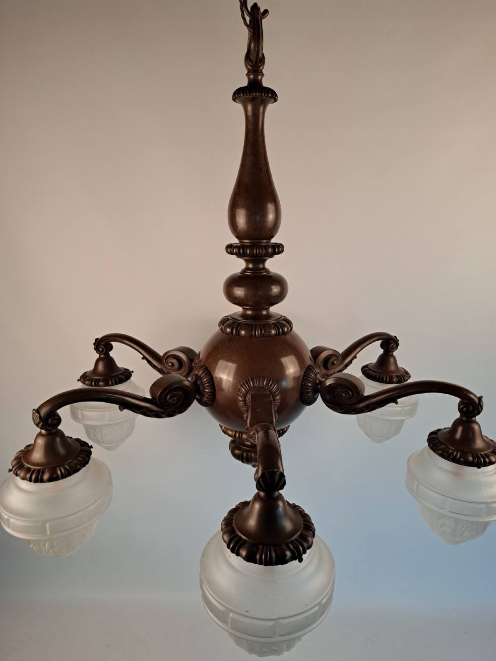 A five-arm dark bronze chandelier featuring a central turned stem, curved scroll arms, and downward-facing frosted glass shades. View XXIII