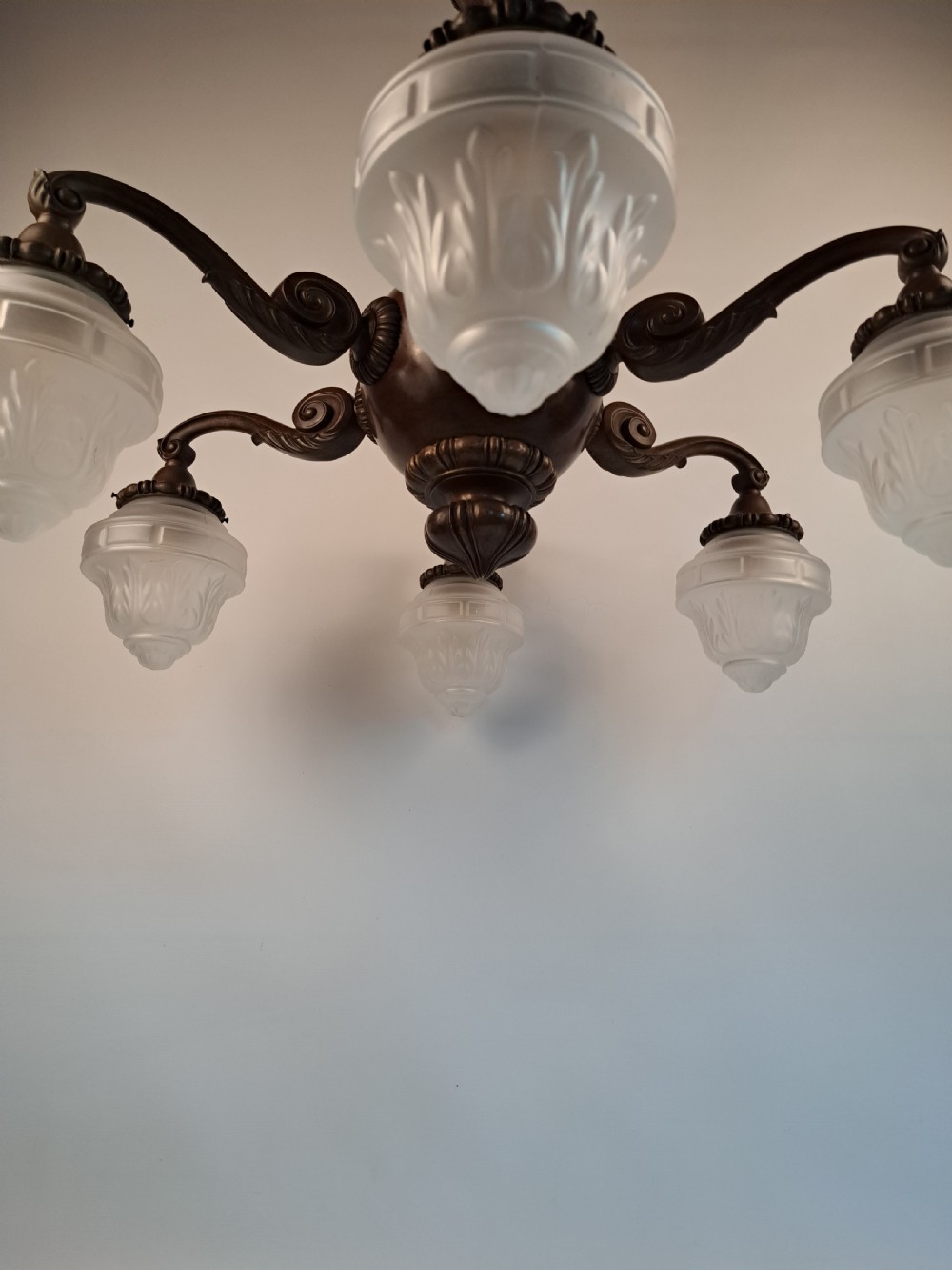 A five-arm dark bronze chandelier featuring a central turned stem, curved scroll arms, and downward-facing frosted glass shades. View XXVI