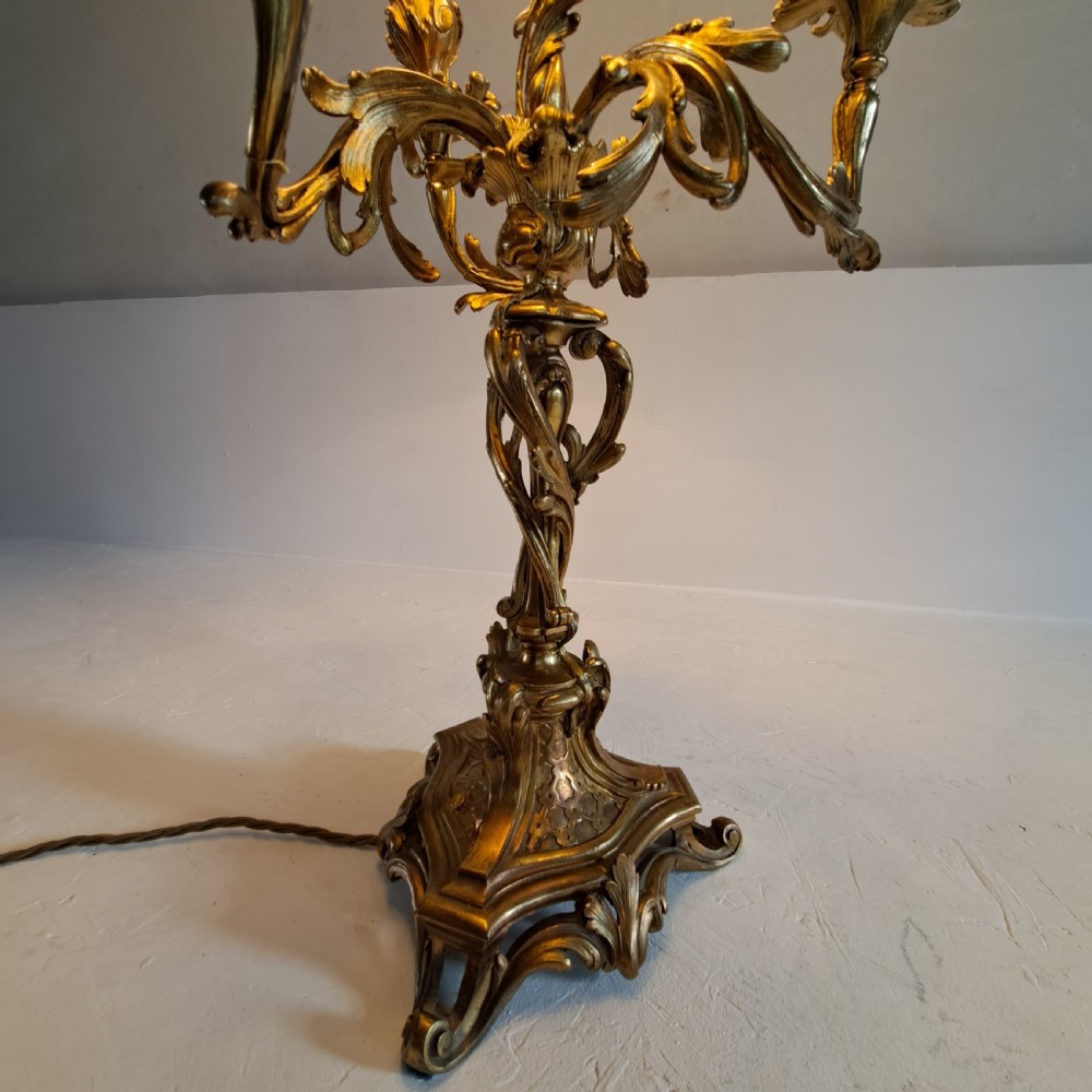 An ornate four-light gilt bronze candelabra table lamp in Rococo Revival style with flared fabric shades and cast scrollwork. View III