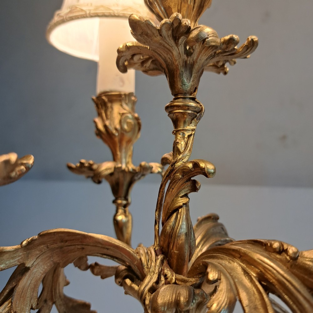 An ornate four-light gilt bronze candelabra table lamp in Rococo Revival style with flared fabric shades and cast scrollwork. View V