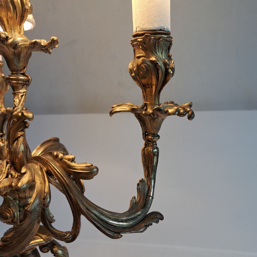 An ornate four-light gilt bronze candelabra table lamp in Rococo Revival style with flared fabric shades and cast scrollwork. View VIII