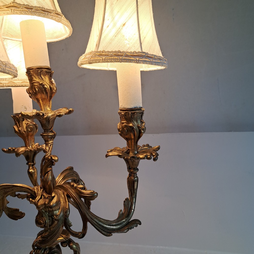 An ornate four-light gilt bronze candelabra table lamp in Rococo Revival style with flared fabric shades and cast scrollwork. View IX