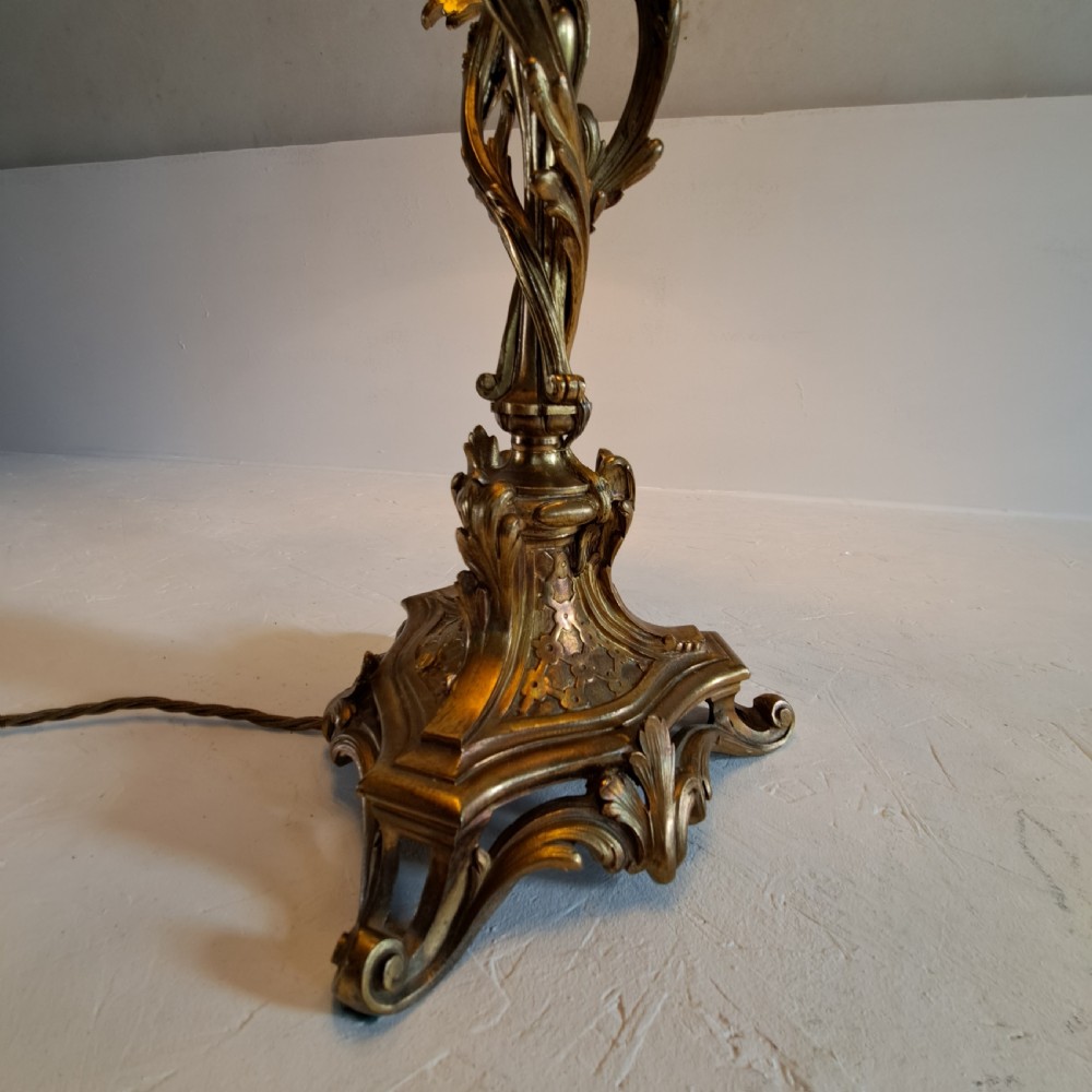 An ornate four-light gilt bronze candelabra table lamp in Rococo Revival style with flared fabric shades and cast scrollwork. View XV