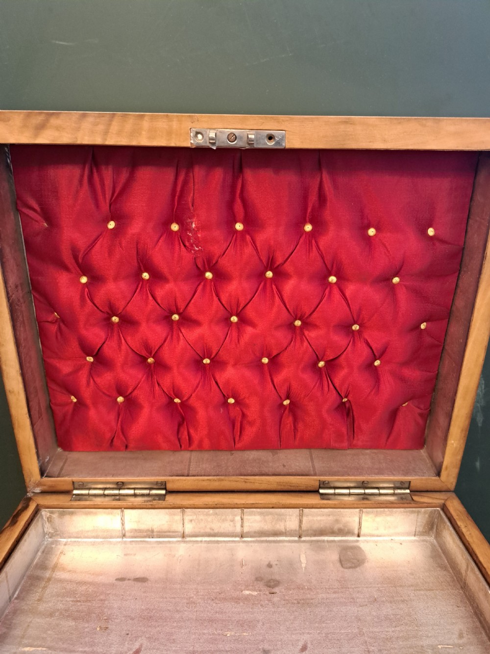 A rectangular blonde walnut jewellery box with a brass keyhole escutcheon and recessed handle on the lid, resting on a dark marble surface. View III