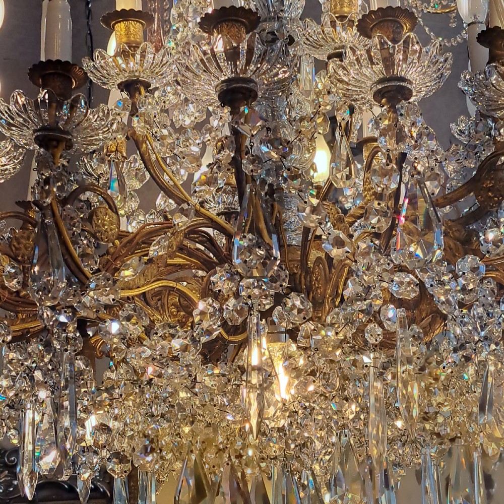 A multi-tiered antique crystal and gilt bronze electrolier chandelier with cascading prisms and candle-style bulb fittings. View XXVI