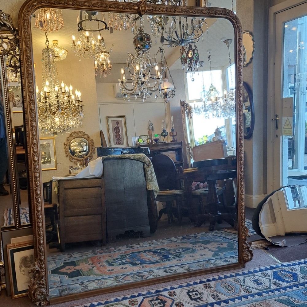 A large rectangular Georgian overmantel mirror featuring a rounded upper frame with gilded bead moulding and decorative foliate corner scrolls. View II