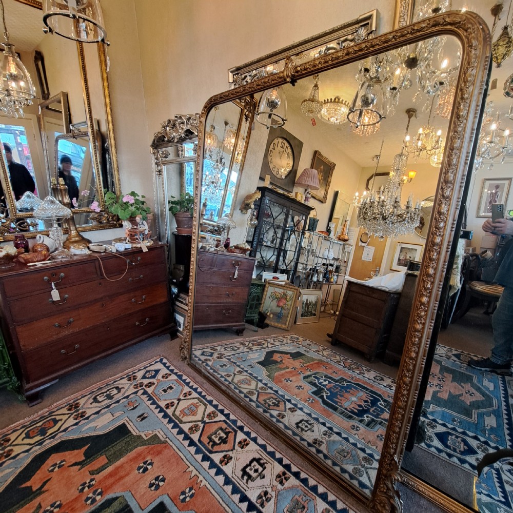 A large rectangular Georgian overmantel mirror featuring a rounded upper frame with gilded bead moulding and decorative foliate corner scrolls. View IV