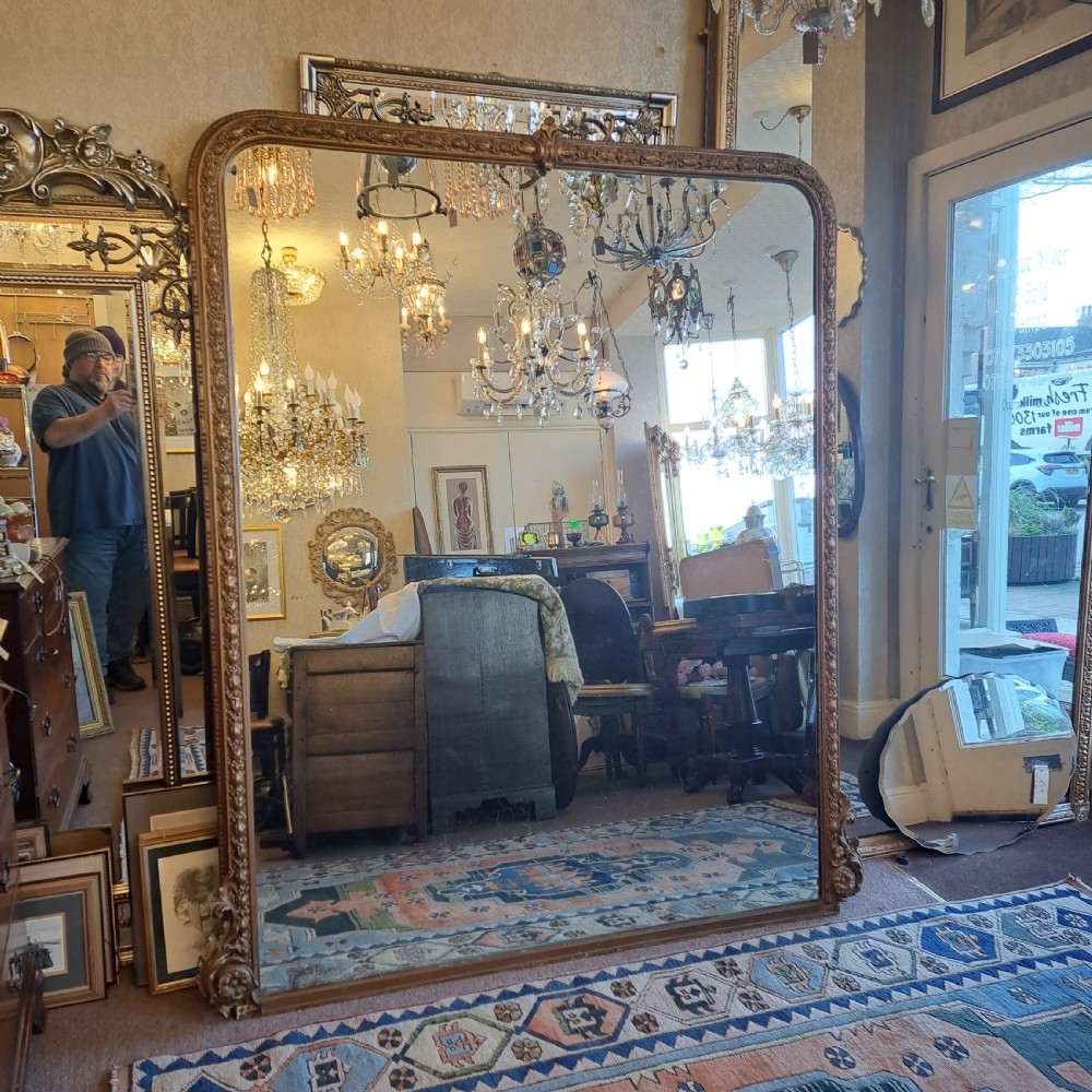 A large rectangular Georgian overmantel mirror featuring a rounded upper frame with gilded bead moulding and decorative foliate corner scrolls. View V