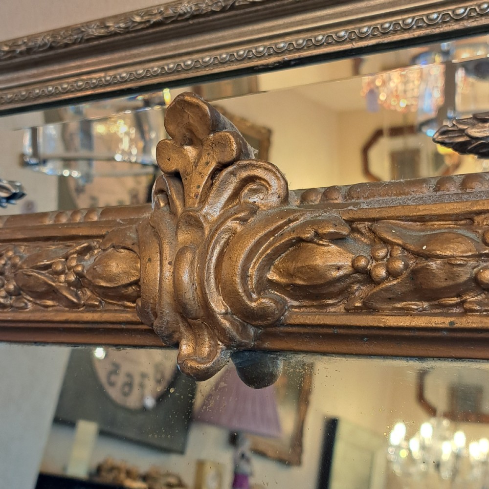 A large rectangular Georgian overmantel mirror featuring a rounded upper frame with gilded bead moulding and decorative foliate corner scrolls. View VII