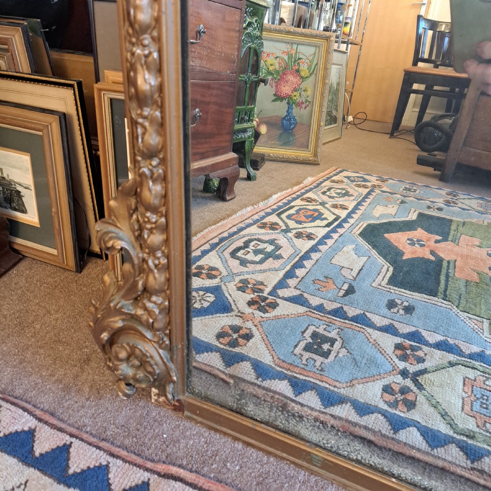 A large rectangular Georgian overmantel mirror featuring a rounded upper frame with gilded bead moulding and decorative foliate corner scrolls. View XII