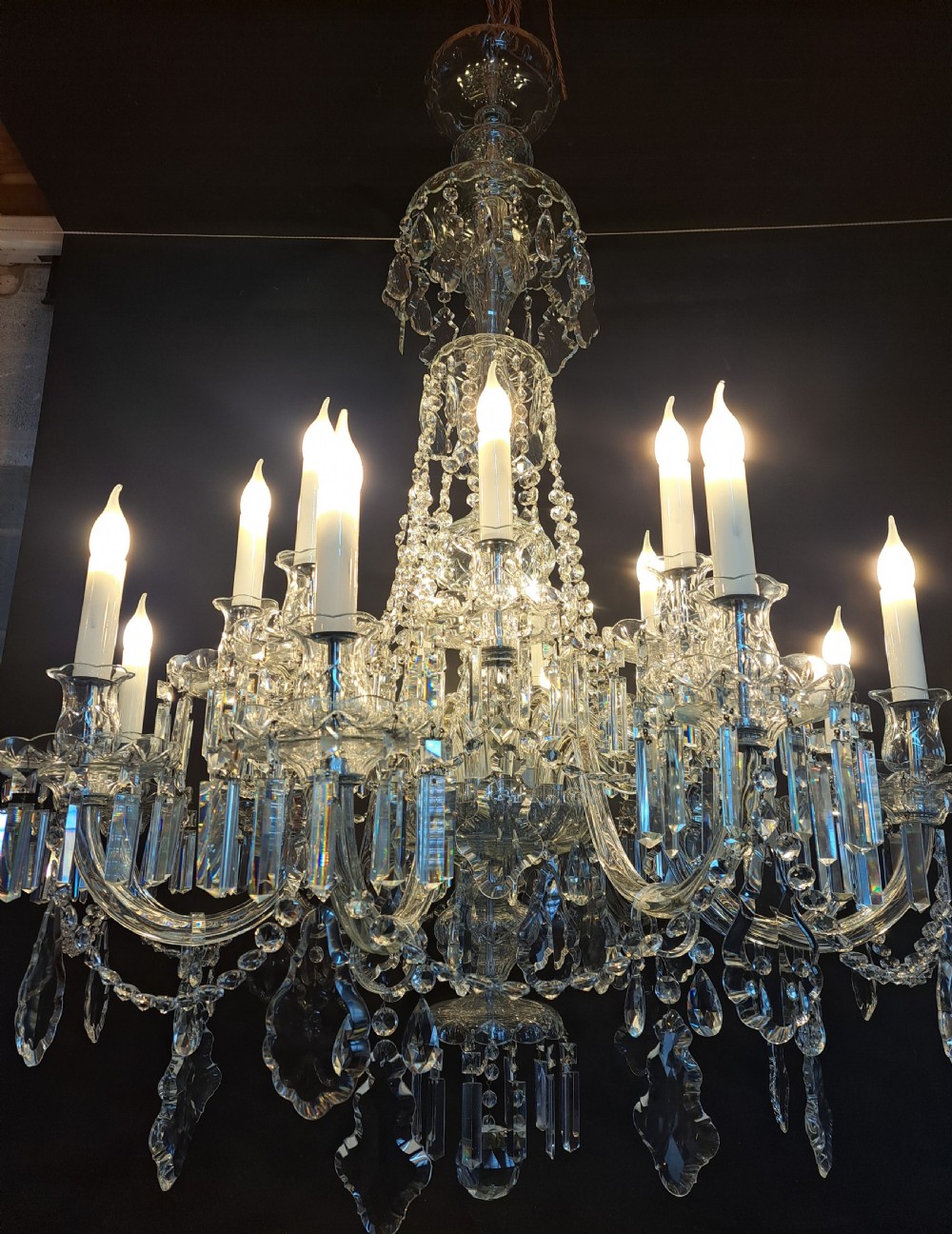 A large multi-arm Bohemian cut crystal chandelier featuring candle-style bulb sleeves, curved glass arms, and faceted crystal drops. View XV