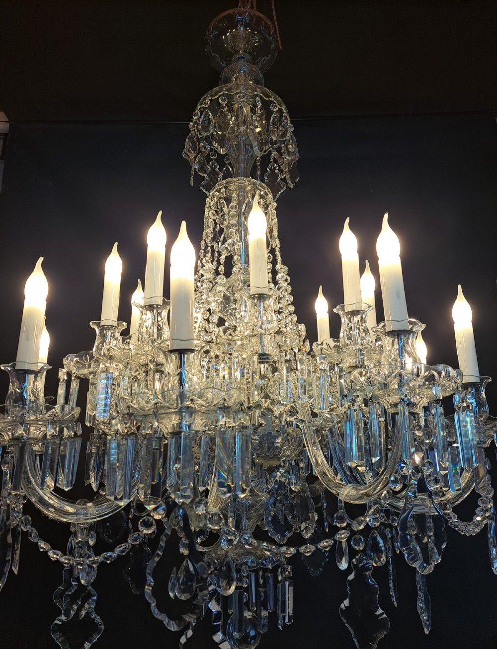 A large multi-arm Bohemian cut crystal chandelier featuring candle-style bulb sleeves, curved glass arms, and faceted crystal drops.