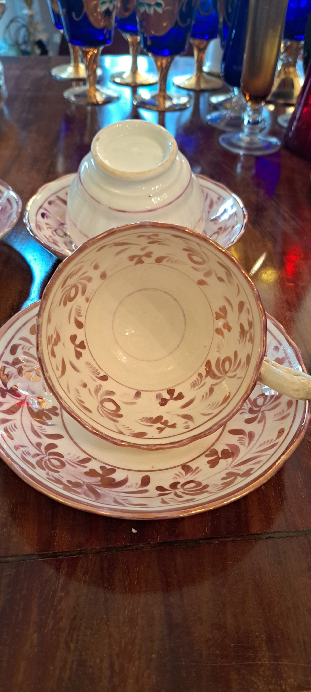 A set of six antique pink lustreware teacups with matching saucers featuring hand-painted botanical foliage patterns on a cream ceramic background. View III