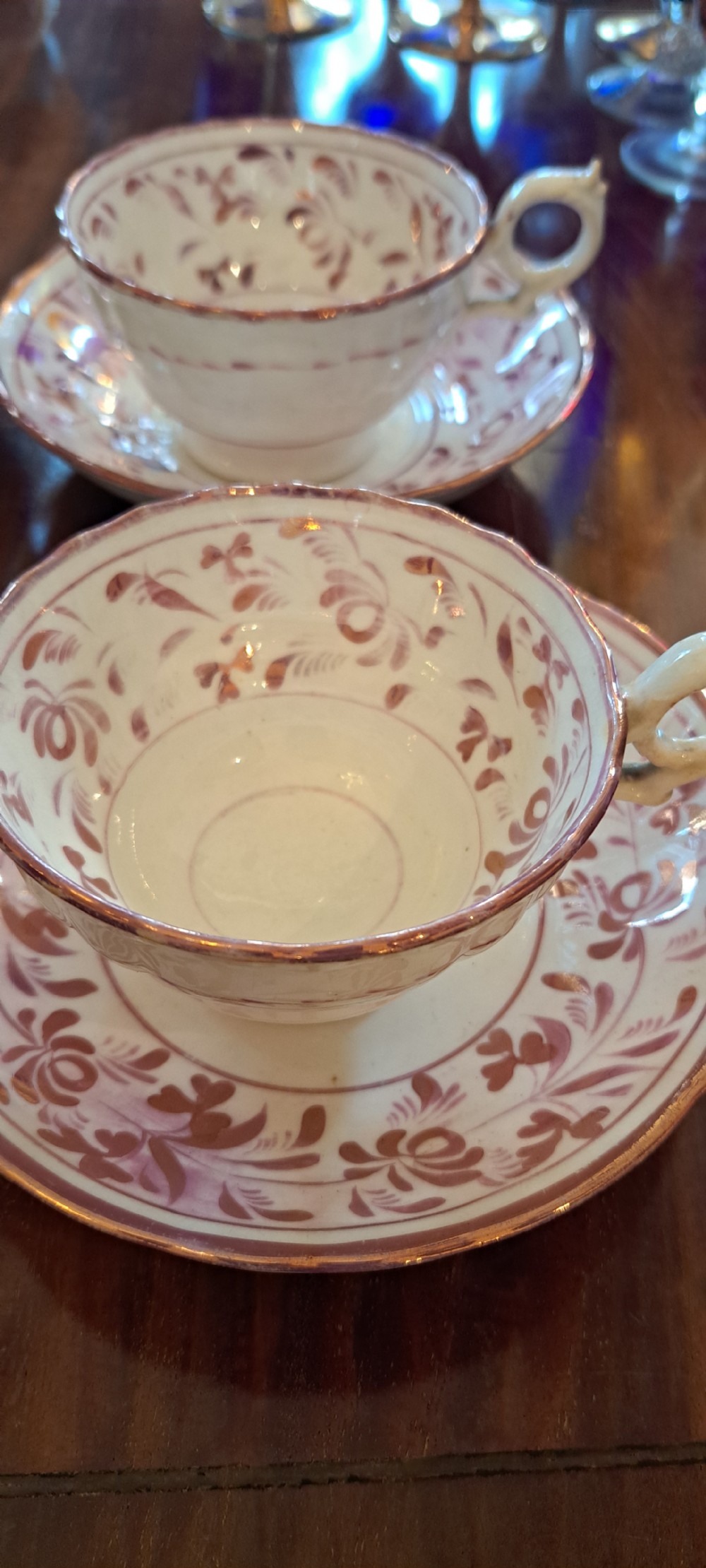 A set of six antique pink lustreware teacups with matching saucers featuring hand-painted botanical foliage patterns on a cream ceramic background. View VII