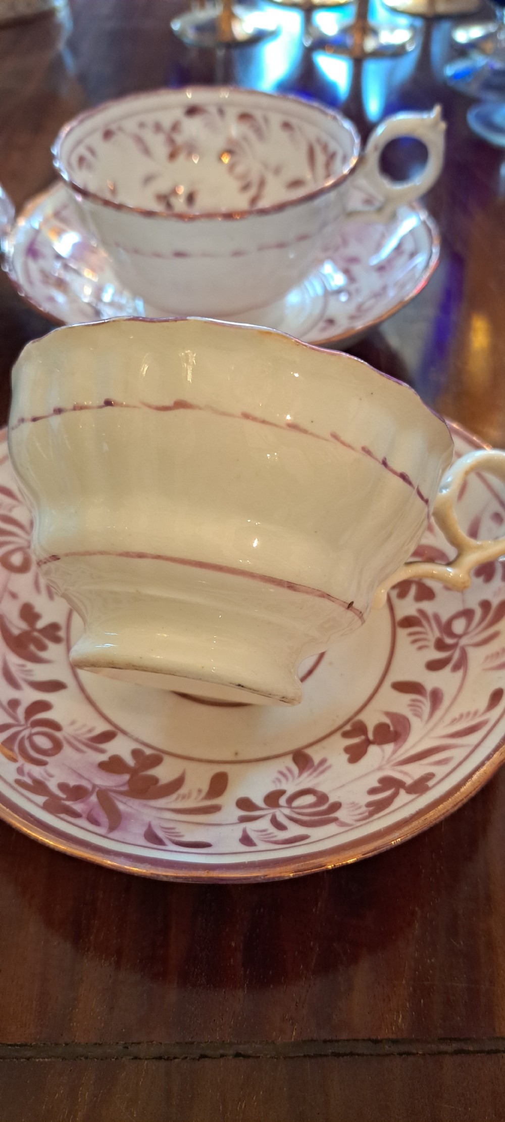 A set of six antique pink lustreware teacups with matching saucers featuring hand-painted botanical foliage patterns on a cream ceramic background. View XI