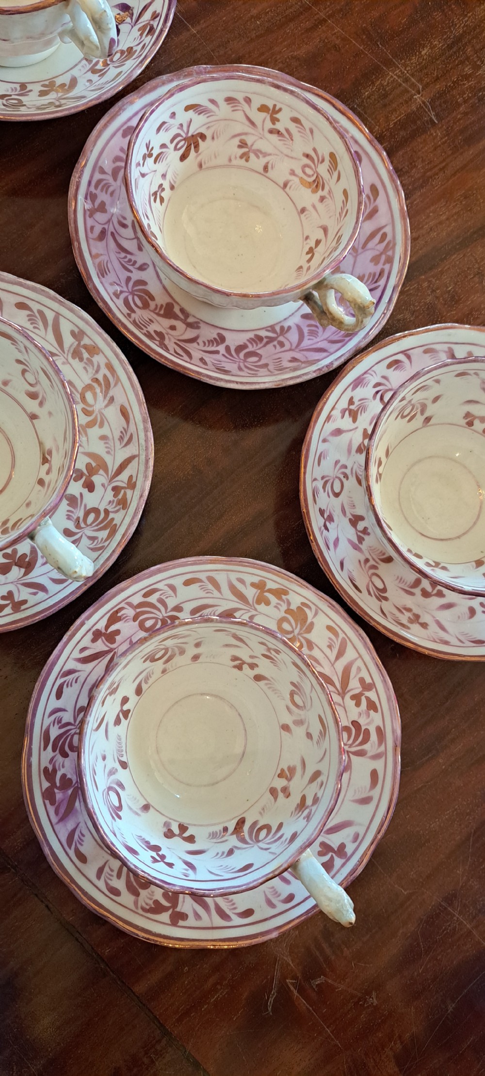A set of six antique pink lustreware teacups with matching saucers featuring hand-painted botanical foliage patterns on a cream ceramic background. View XIII