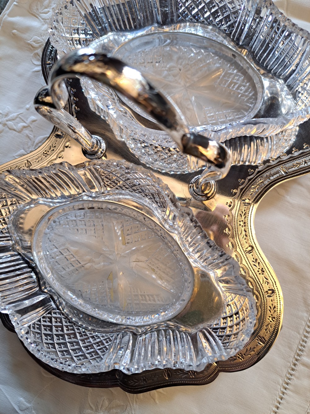 An Edwardian silver-plated relish caddy featuring a central carrying handle and two fitted cut-glass dishes with geometric patterns. View II