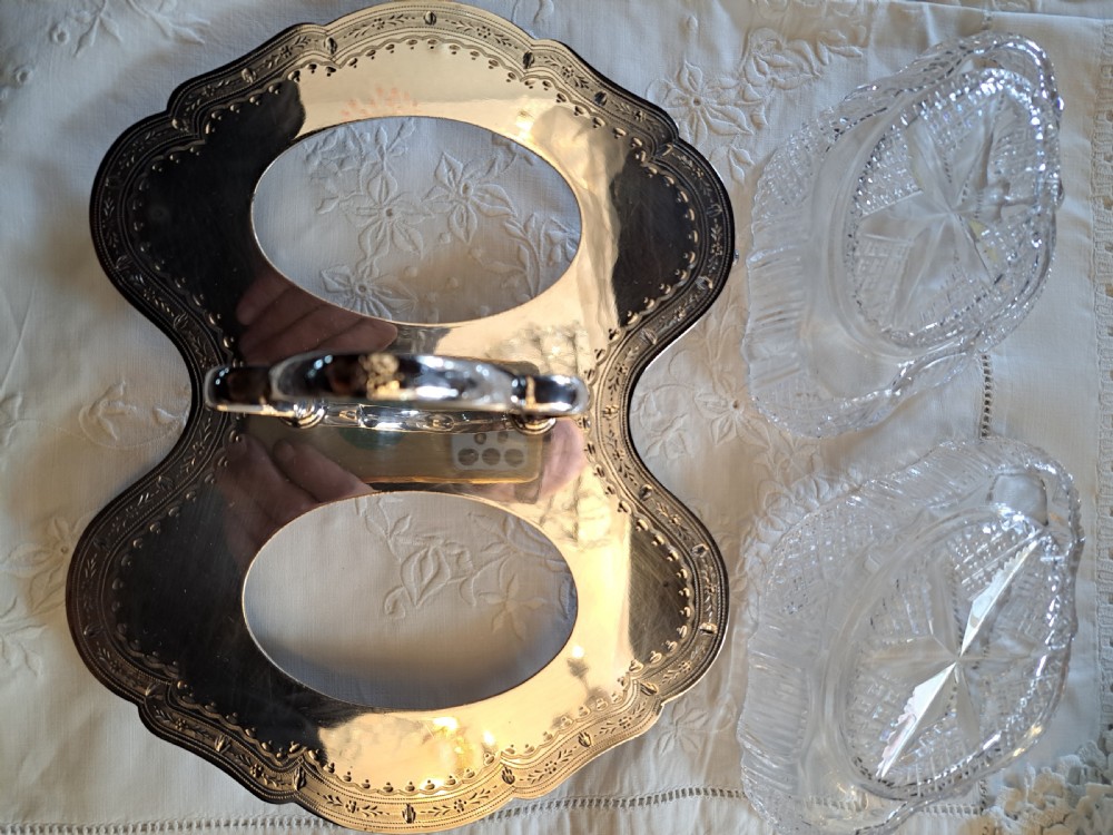 An Edwardian silver-plated relish caddy featuring a central carrying handle and two fitted cut-glass dishes with geometric patterns. View V
