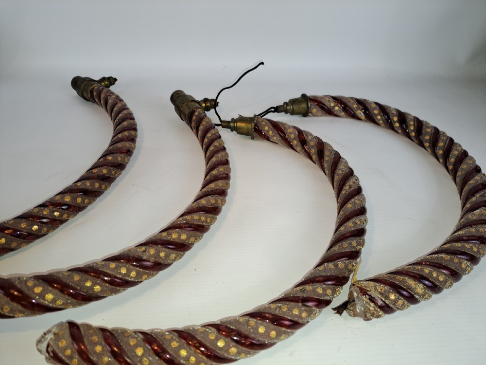 A set of four curved Bohemian ruby glass chandelier arms featuring twisted spiral patterns highlighted with gold enamelled dots and brass threaded mounts.