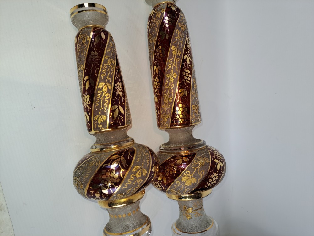 A pair of antique ruby red and frosted glass chandelier stems decorated with spiral gilt grapevine patterns.