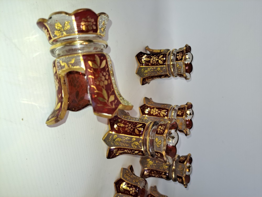 An assortment of ruby stained glass candle nozzles and capitals featuring etched floral motifs and scalloped gilded borders. View IV