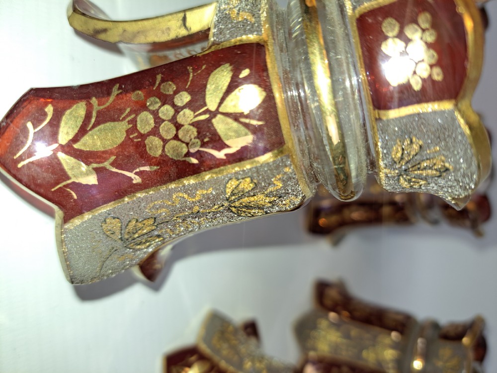 An assortment of ruby stained glass candle nozzles and capitals featuring etched floral motifs and scalloped gilded borders. View III