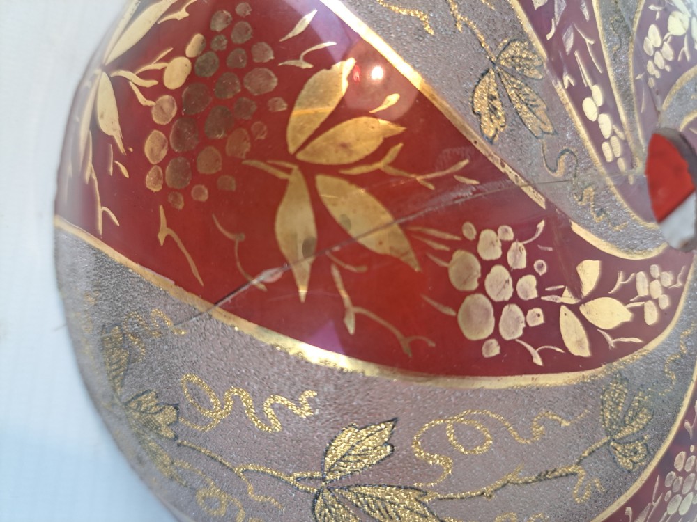 A hemispherical ruby red glass chandelier bowl featuring frosted diagonal panels, gilded grapevine motifs, and a central circular hole. View III