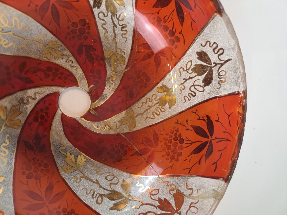 A hemispherical ruby red glass chandelier bowl featuring frosted diagonal panels, gilded grapevine motifs, and a central circular hole. View IV