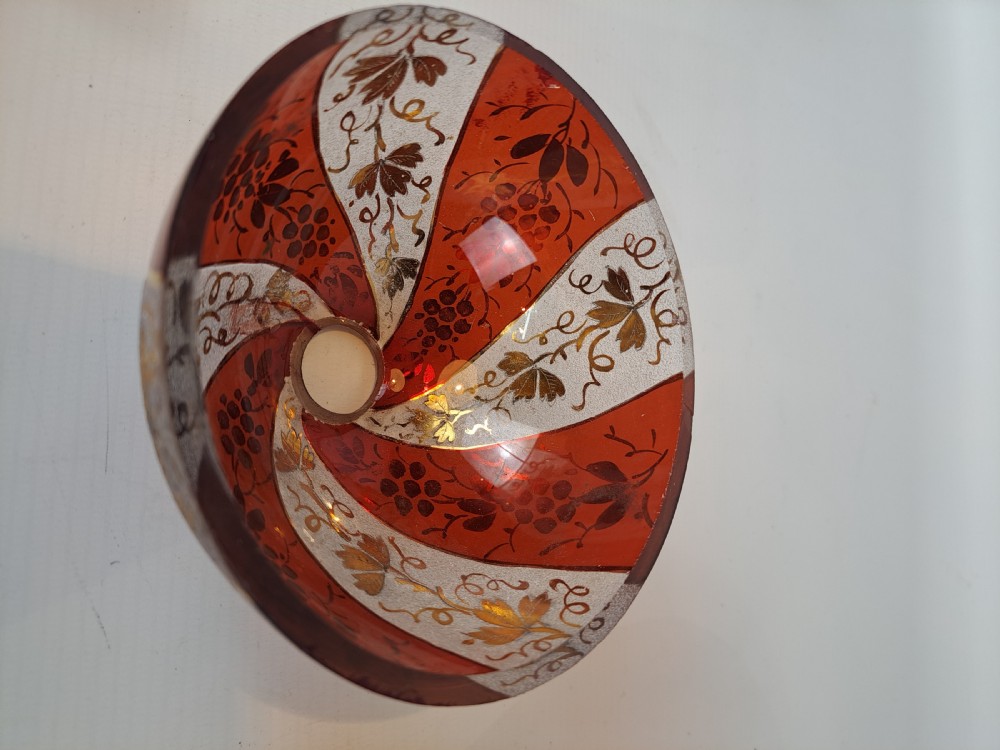 A hemispherical ruby red glass chandelier bowl featuring frosted diagonal panels, gilded grapevine motifs, and a central circular hole. View V