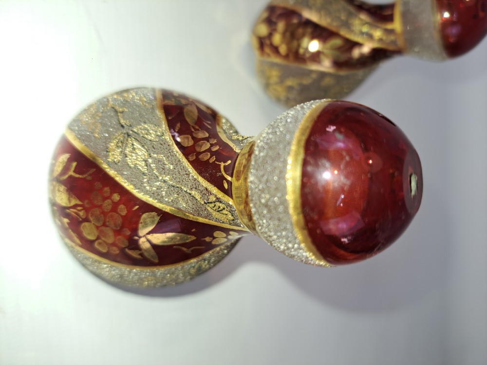 A pair of ruby red glass decorative bells featuring hand-painted gold foliage motifs and textured gilded bands. View III